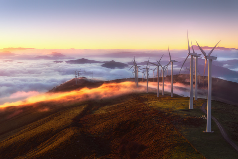 Row of wind turbines on mountaintop with a sunset background