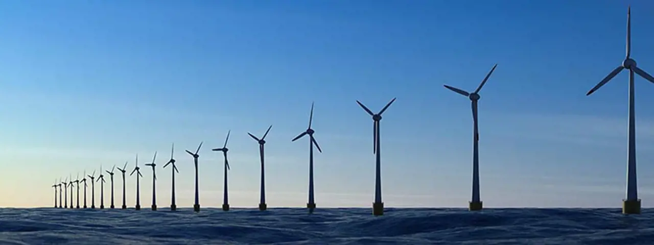 Row of offshore wind turbines with blue sky background