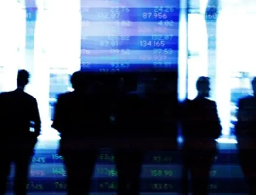 Silhouttes of people stood infront of abstract financial listings board