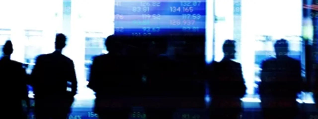 Silhouttes of people stood infront of abstract financial listings board