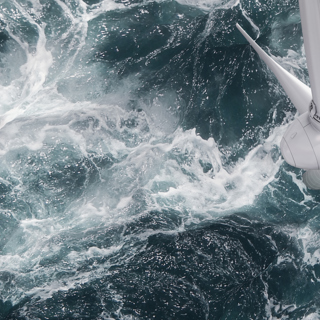 Overhead view of offshore wind turbine with waves crashing around
