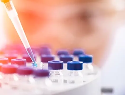 Scientist filling small glass medicine bottles with a pipette