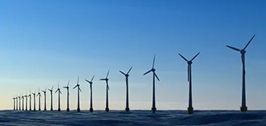 A line of offshore wind turbines with blue skies