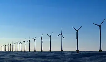 A line of offshore wind turbines with blue skies